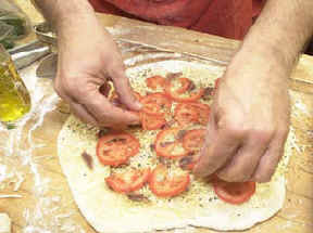 Putting together an anchovy and tomato pizza!